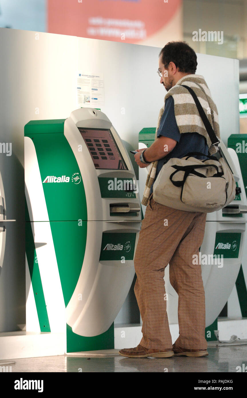 Uomo con bagaglio a mano utilizzando un Alitalia apparecchio di check-in  self-service nel terminale Foto stock - Alamy