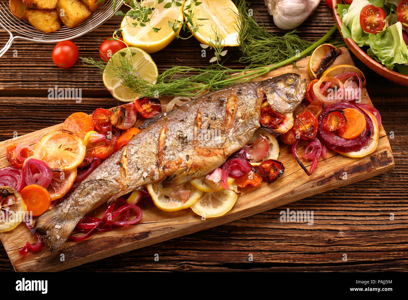 Grigliate di pesce con verdure e patate su sfondo di legno Foto Stock