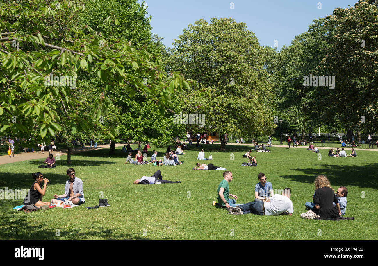 Ufficio lavoratori rilassarsi in St James Park a pranzo su una soleggiata giornata di primavera a Londra, Regno Unito Foto Stock