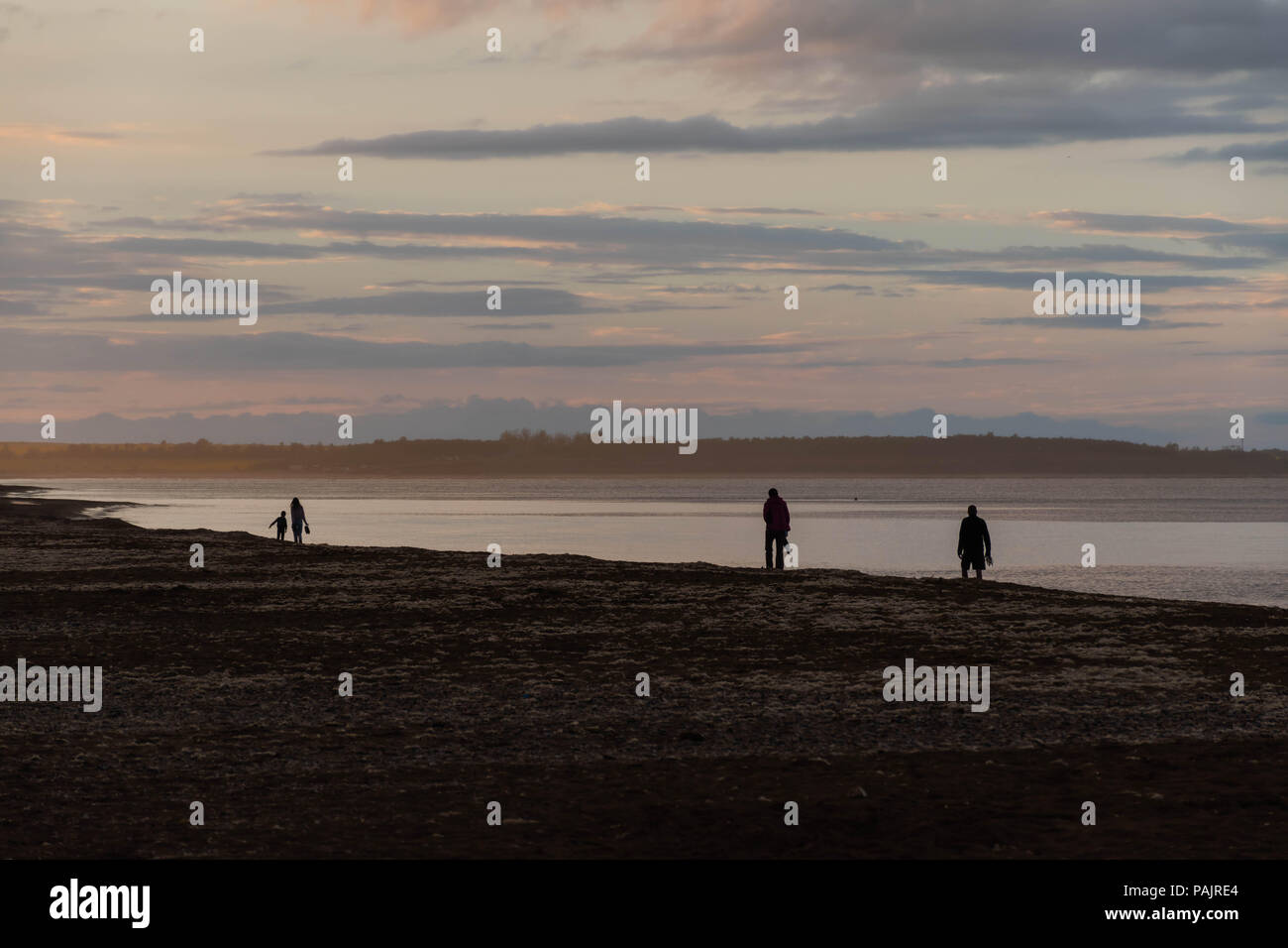 Persone come sagome nel tramonto ad esplorare e terra incognita da mare Foto Stock