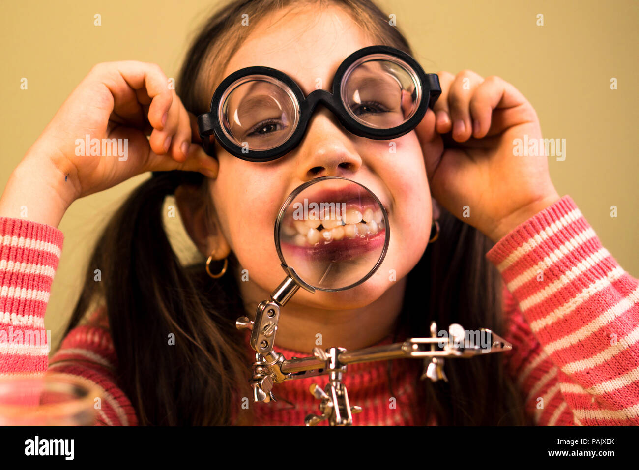 Bambina mostra i suoi denti nella lente di ingrandimento. Bambino  scienziato Foto stock - Alamy