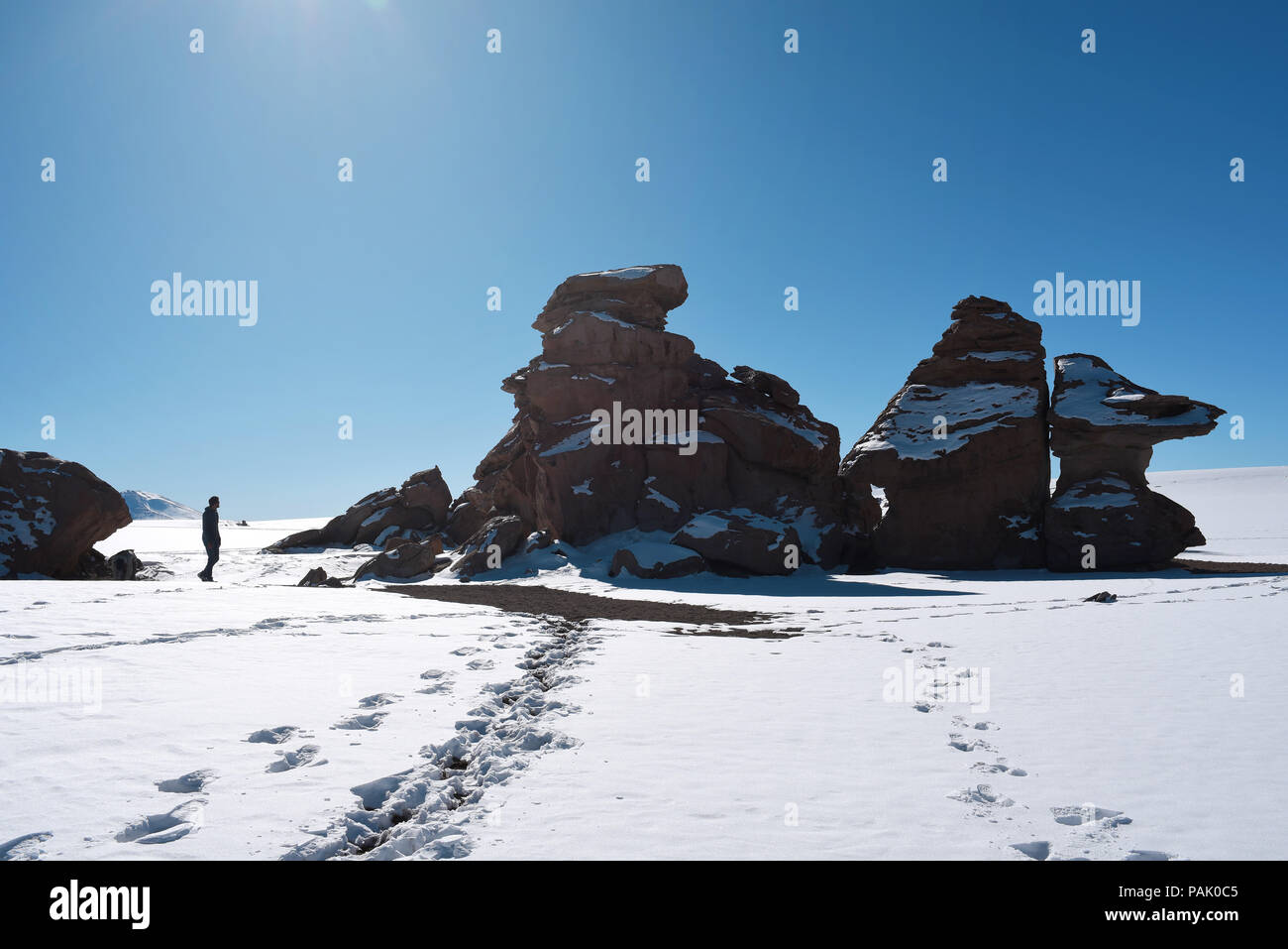 Uomo che cammina nella coperta di neve paesaggio surreale della 'Árbol de Piedra all' interno di Eduardo Avaroa fauna Andina riserva nazionale, Bolivia. Foto Stock