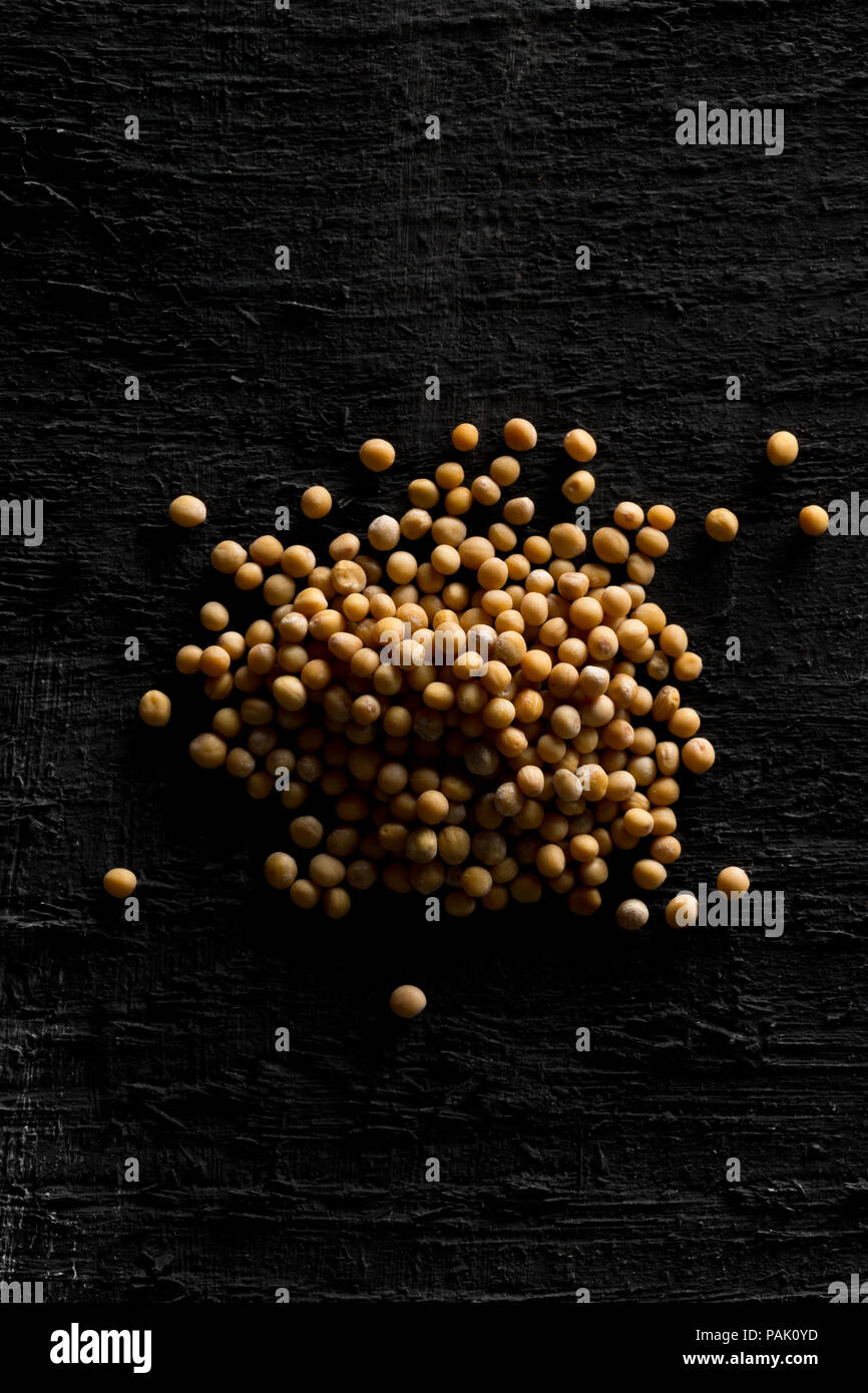Cumulo di materie, non trasformati seme di senape Semi sul nero lo sfondo della tabella Foto Stock