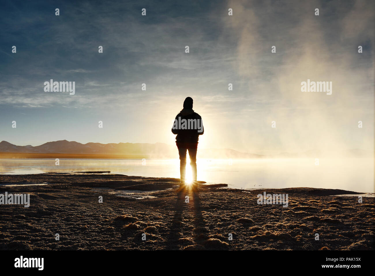 Silhouette di donna osservare il tramonto a Termas de Polques (hot springs entro il Eduardo Avaroa fauna Andina Riserva Nazionale), Bolivia Foto Stock