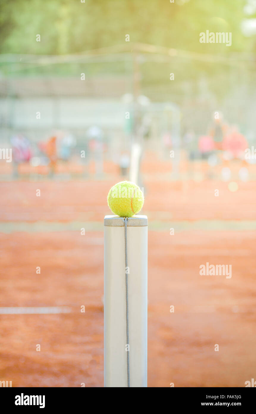 Palla da tennis su un netto post con una corte di argilla su un luminoso giorno caldo e soleggiato con un morbido effetto applicato Foto Stock