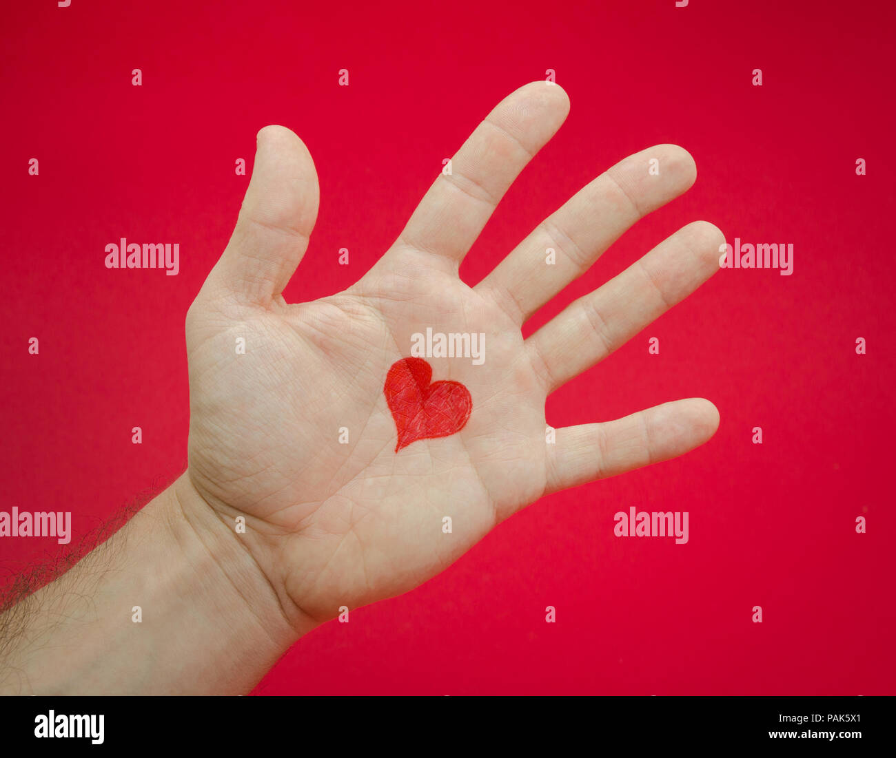 Le emozioni e i sentimenti da amare qualcuno ha suggerito da un uomo di aprire Palm con un cuore su un rosso sfondo seri danni alle persone . Foto Stock