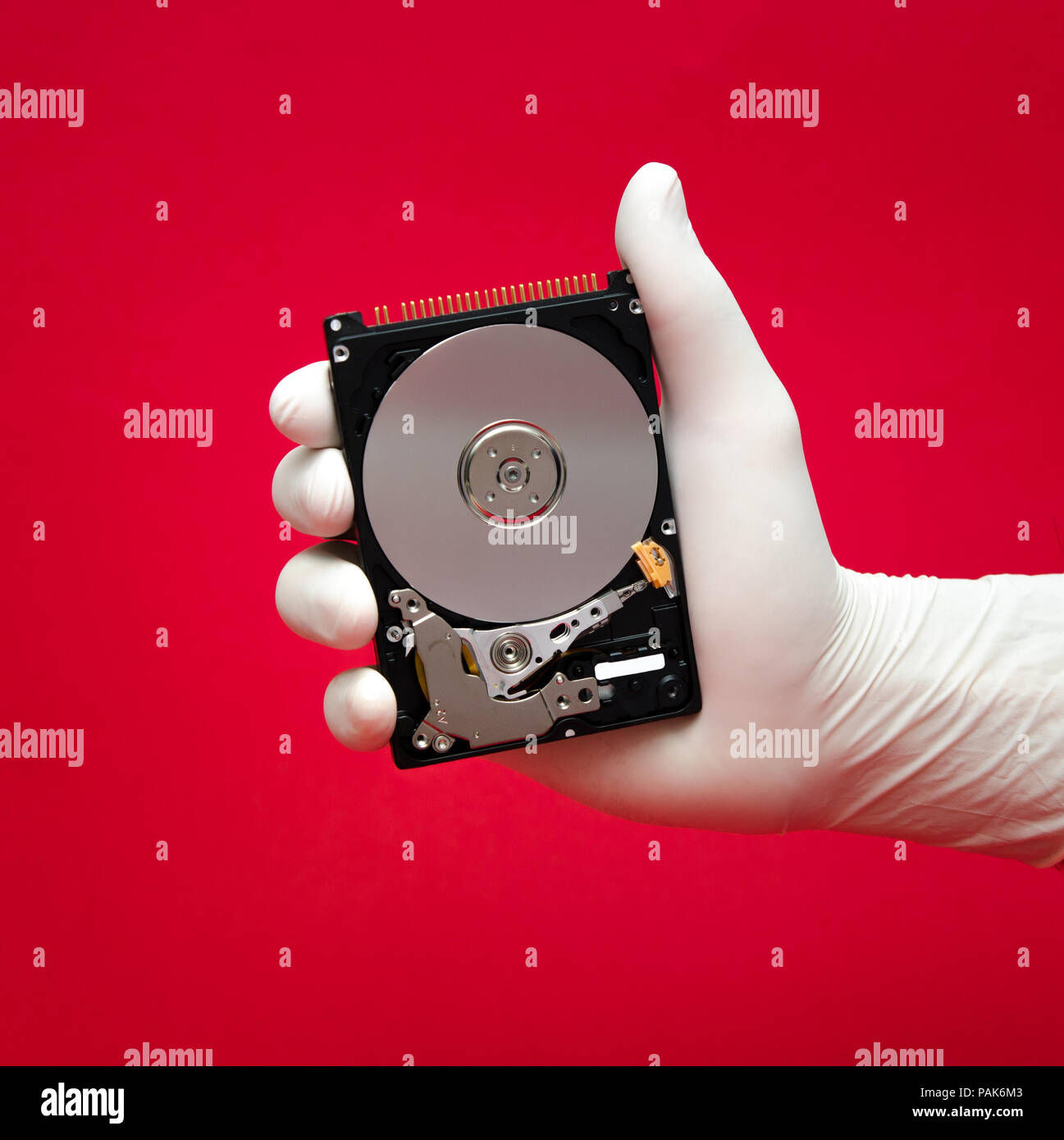 Un disco rigido è detenuta da uno scienziato o un aggiustatore la mano su un rosso con file importanti in attesa di essere recuperati Foto Stock