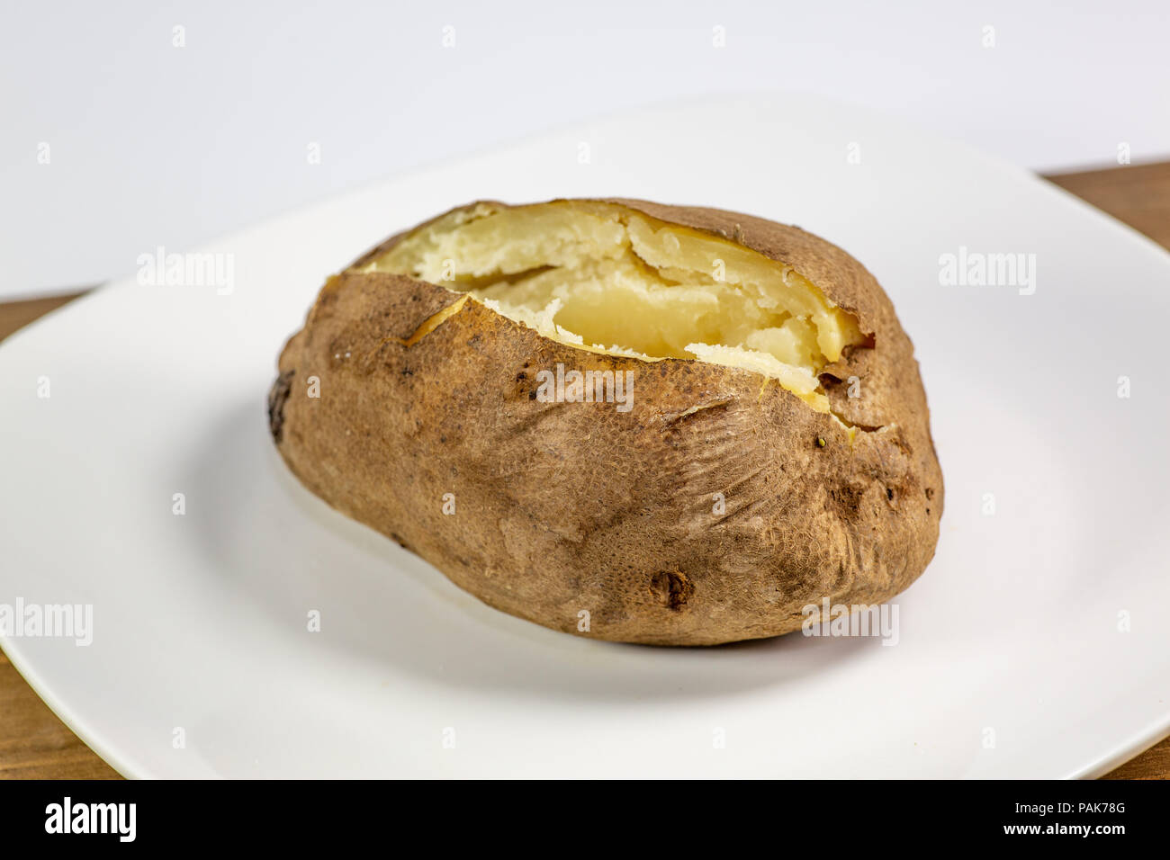 Completamente caricato di patate al forno su una piastra bianca sul tavolo della cucina Foto Stock