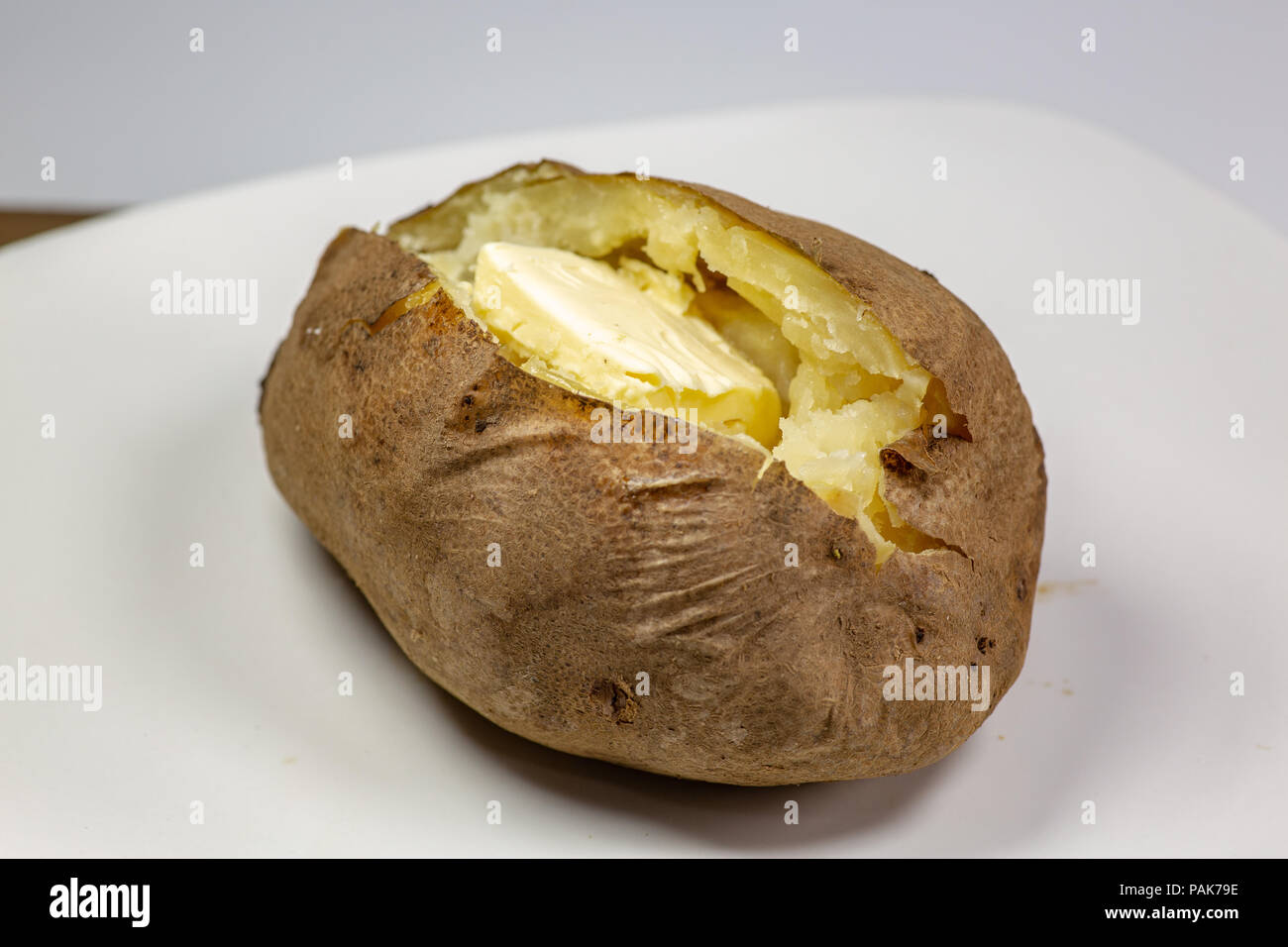 Completamente caricato di patate al forno su una piastra bianca sul tavolo della cucina Foto Stock