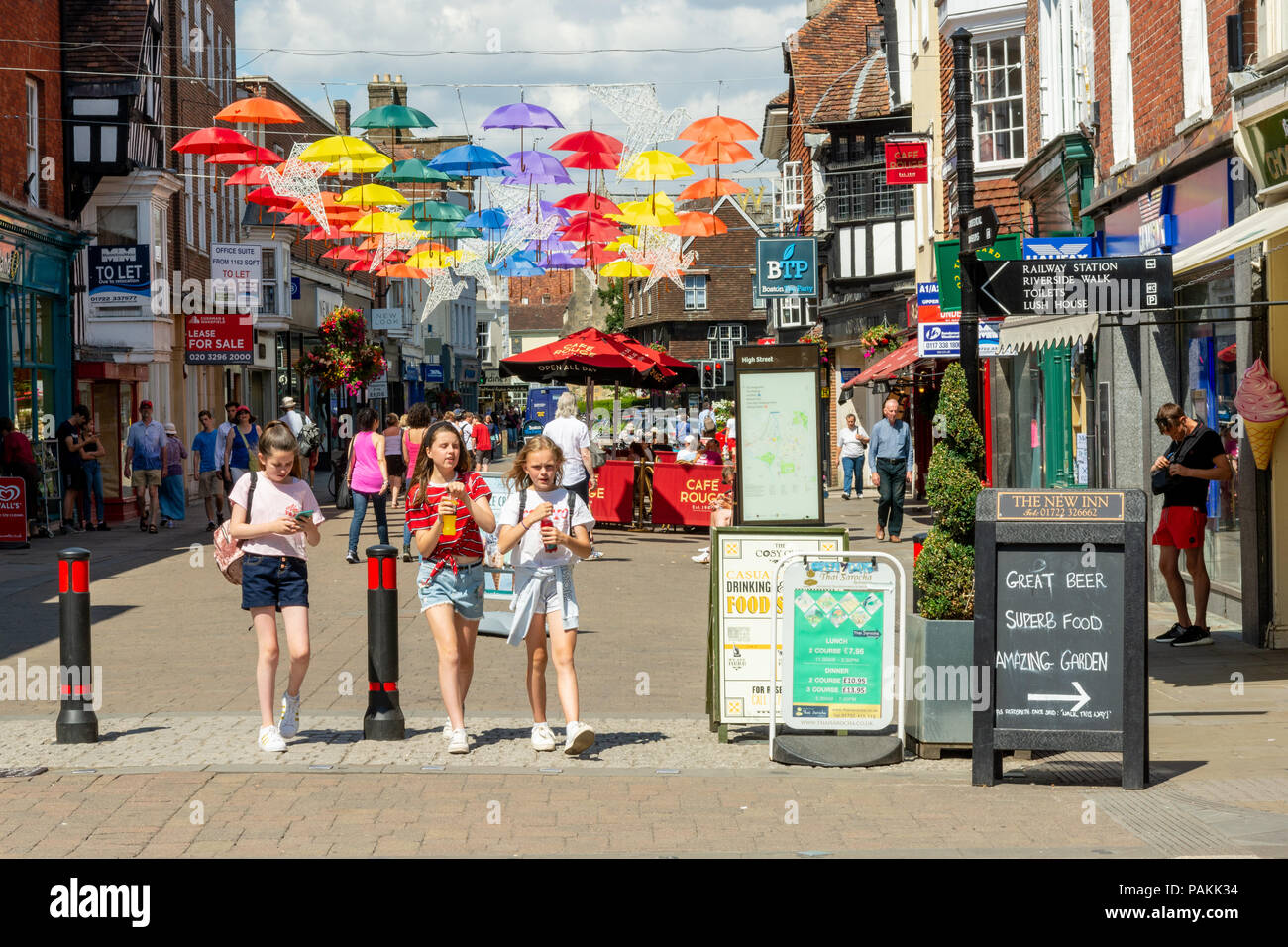 Salisbury, Wiltshire, Regno Unito, 24th luglio 2018, Meteo: Caldo e soleggiato nella città cattedrale con temperature che si aggirano verso i 30 gradi. Un colorato ombrello arte installazione proietta un po 'di ombra su High Street. Foto Stock