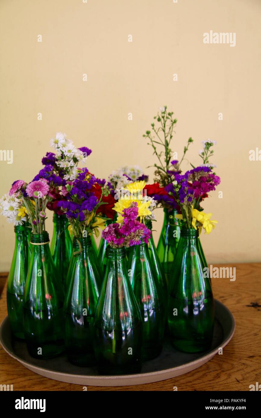 Verde bottiglie in vetro con fiori su un vassoio Foto Stock