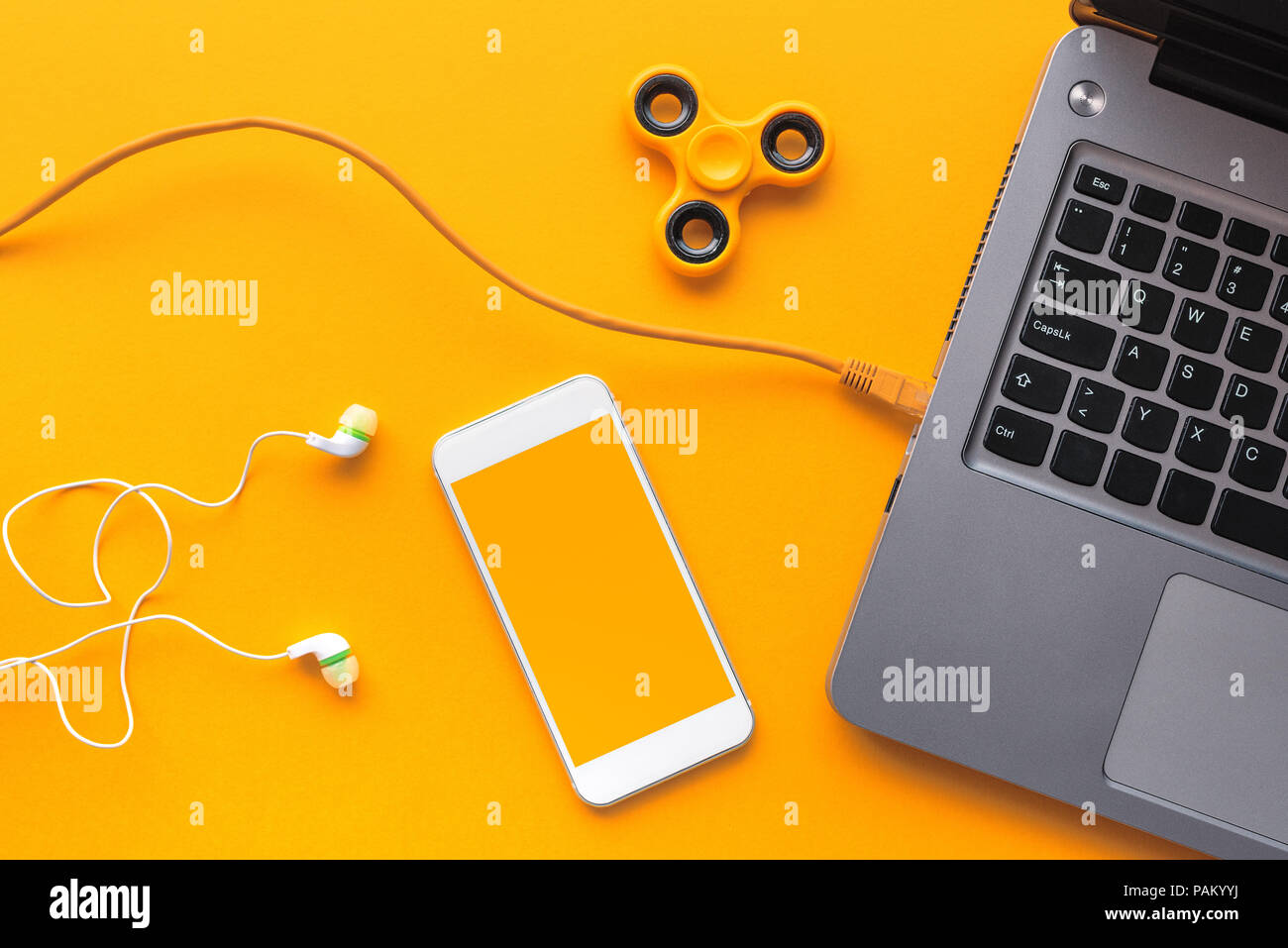 Gadget appartenenti al giovane - laptop e smart phone con auricolari e agitano: spinner in vista superiore piatta stile laici Foto Stock
