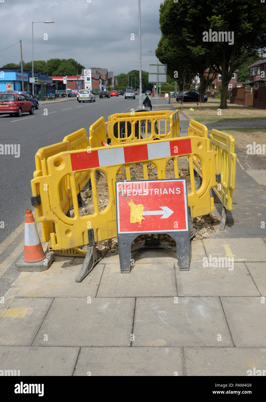 Rosso temporaneo, i pedoni tenere la destra cartello sul marciapiede davanti di plastica gialla di barriere di sicurezza a bury LANCASHIRE REGNO UNITO Foto Stock