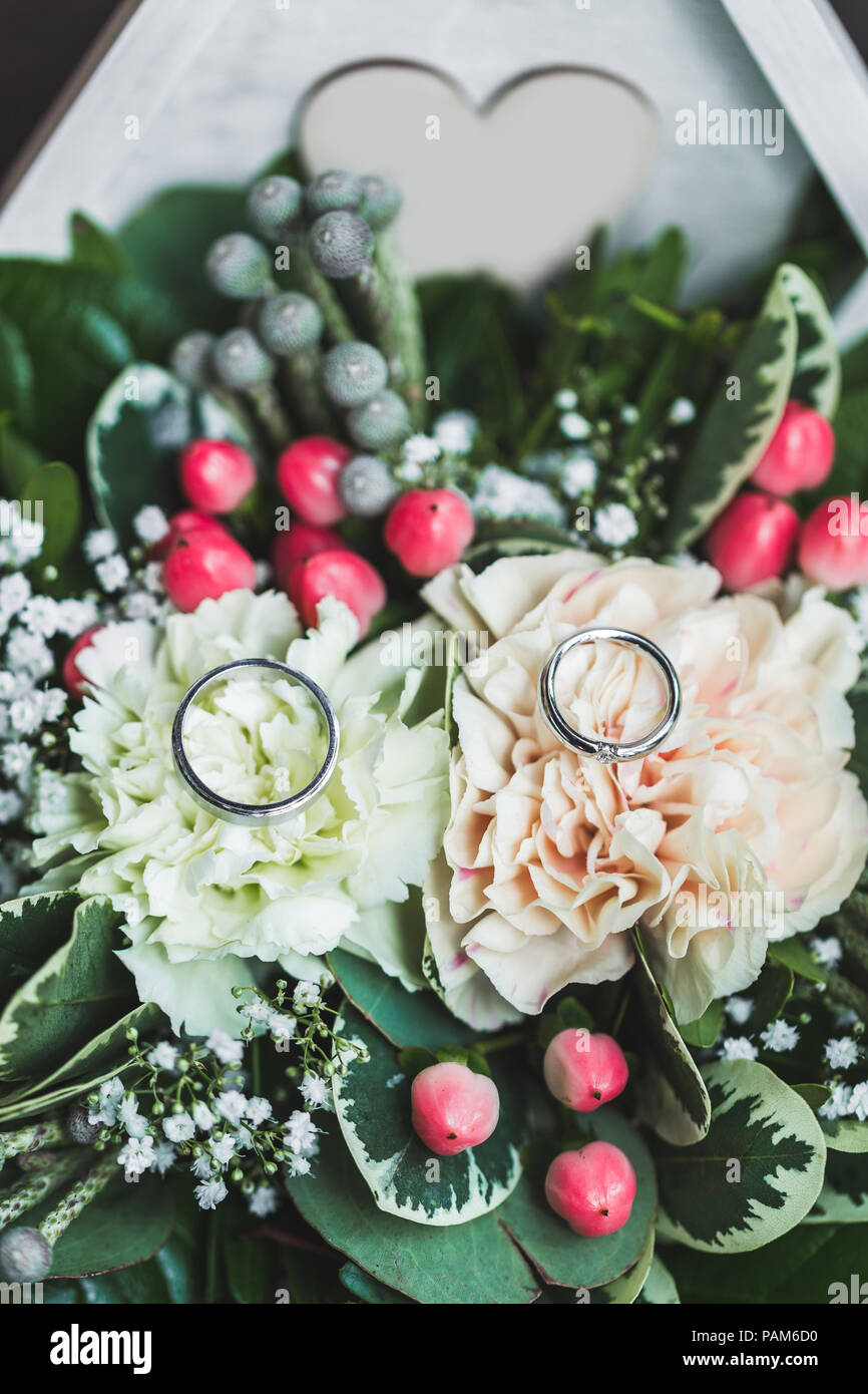 Due oro bianco fedi in scrigno di close-up con fiori freschi per la cerimonia di nozze Foto Stock