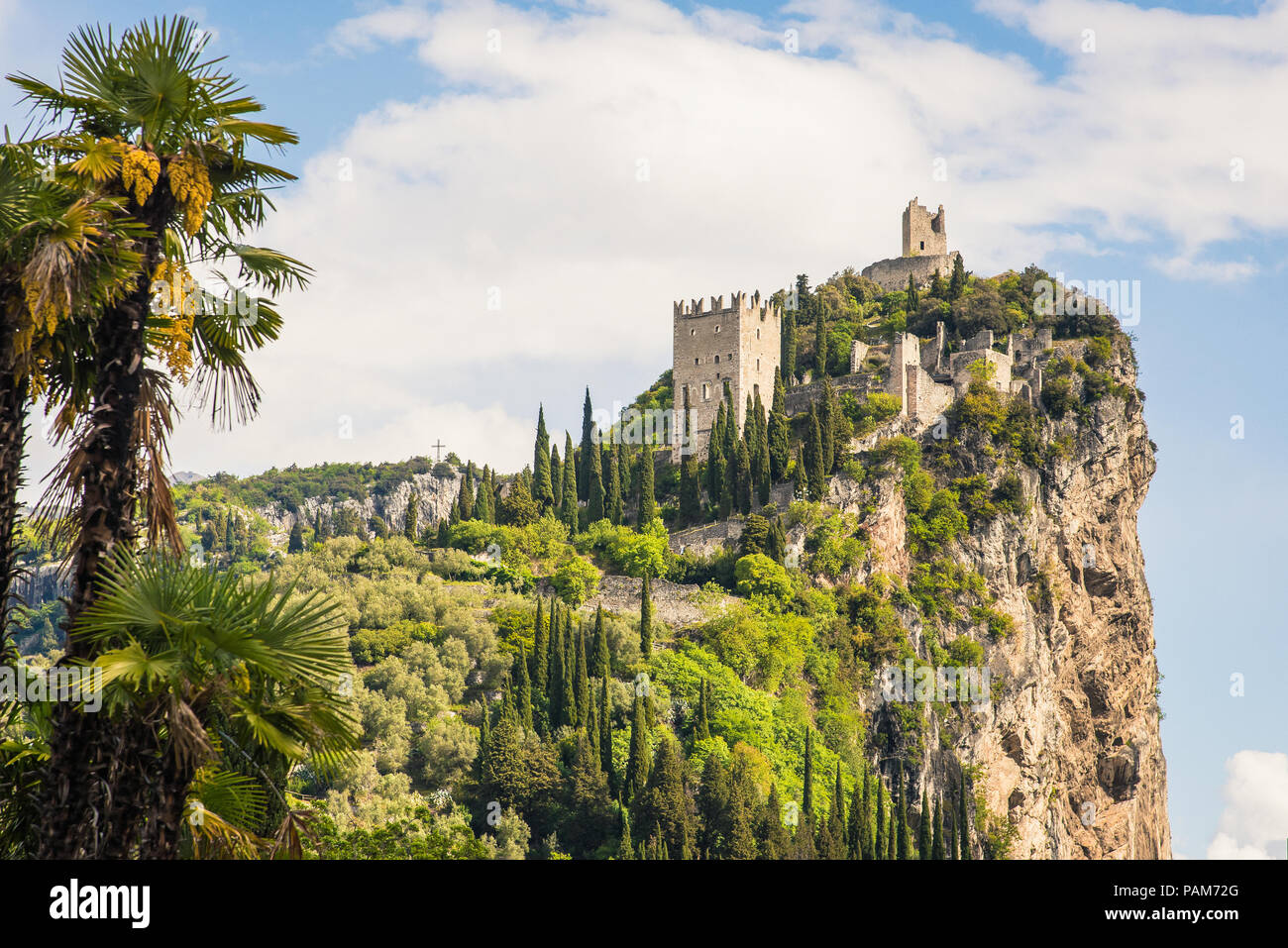 Il castello in rovina di Arco che siede su uno sperone roccioso sopra il fiume Sarca, in Trentino, regione dell'Italia, in bright sole primaverile Foto Stock