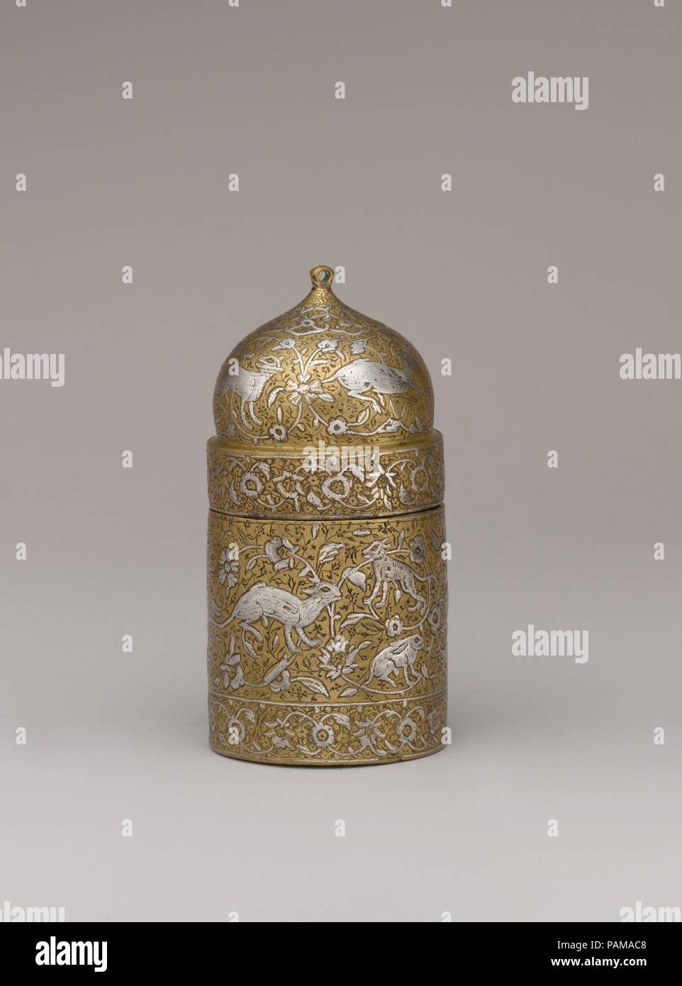 Inkwell con motivi floreali e immagini di animali. Dimensioni: H. 3 5/8 in. (9.2 cm). Data: XVI secolo. Questo dawat cilindrica (inkwell) con un coperchio a cupola una volta montare in un metallo penbox, dove è stata fissata per mezzo di una linea di saldatura lungo la sua linea di giunzione. Argento intarsiato costituisce la principale decorazione floreale di vigne e di animali e inciso e inseguito motivi floreali occupano lo sfondo. Un piercing nel coperchio suggerisce che un anello può avere una volta attenuato la apertura e la chiusura della inkwell. A cui si fa riferimento in persiano di poesie e storie come presto come il decimo secolo, inkwells cilindrico con coperchi a cupola era produrre Foto Stock