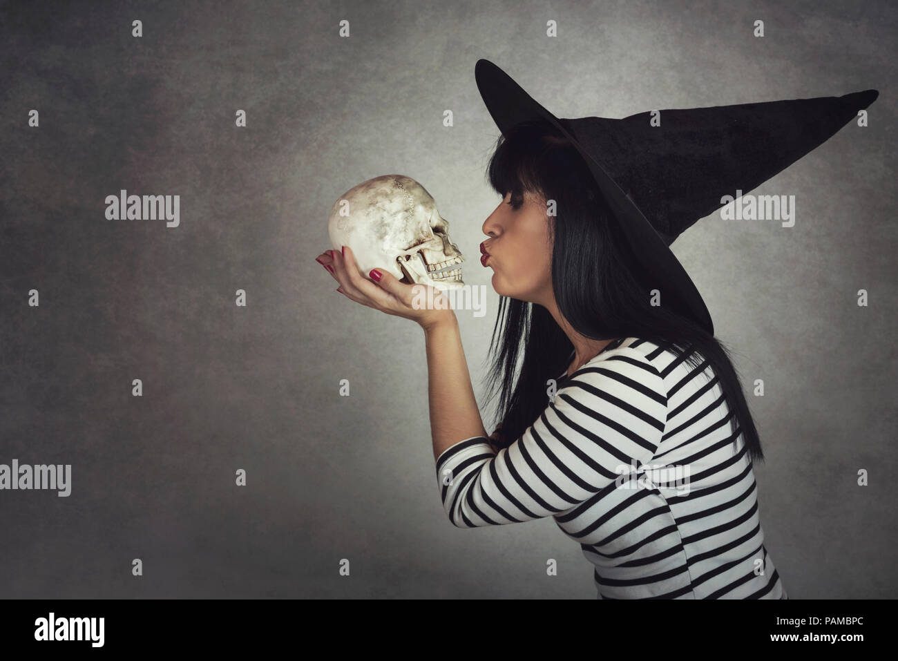 Giovane donna baci un cranio in halloween Foto Stock