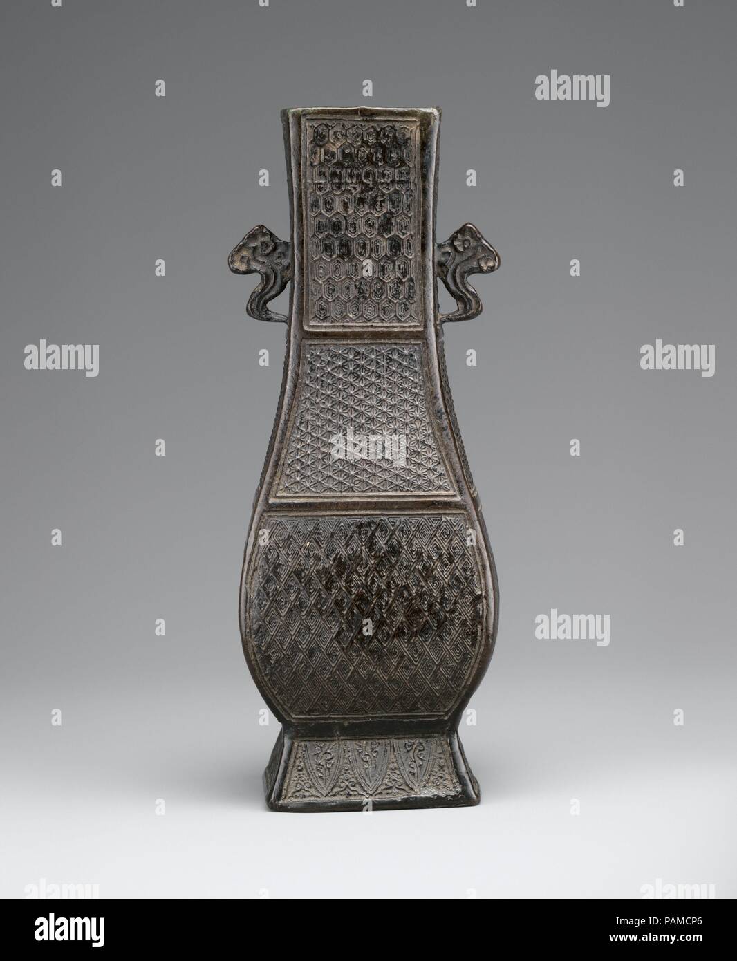 Vaso. Cultura: la Cina. Dimensioni: H. 7 5/8 in. (19,4 cm); W. 2 3/4 in. (7 cm); D. 2 1/8 in. (5.4 cm). Data: XIII-XIV secolo. Questo vaso sottile ha una sezione rettangolare su un piede strombato, con due a forma di nuvola maniglie fissate ai lati del suo collo. Tutti e quattro i lati del vaso sono decorate, dal collo ai piedi, con motivi geometrici, compresi pannolino a nido d'ape, fiorellino-e-punti pannolino, diamond pannolino, e pendente falde. Tutta la nave è coperto con una calda patina nerastra che non presenta alcuna traccia di essere sepolti sottoterra. Museo: Metropolitan Museum of Art di New York, Stati Uniti d'America. Foto Stock