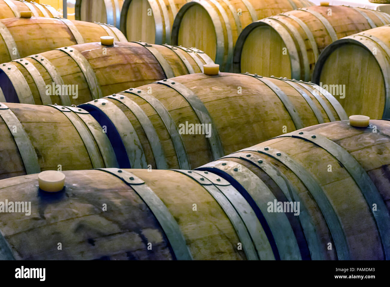 Vecchio e colorate in legno barili di vino in righe all'interno di una cantina di vini Foto Stock