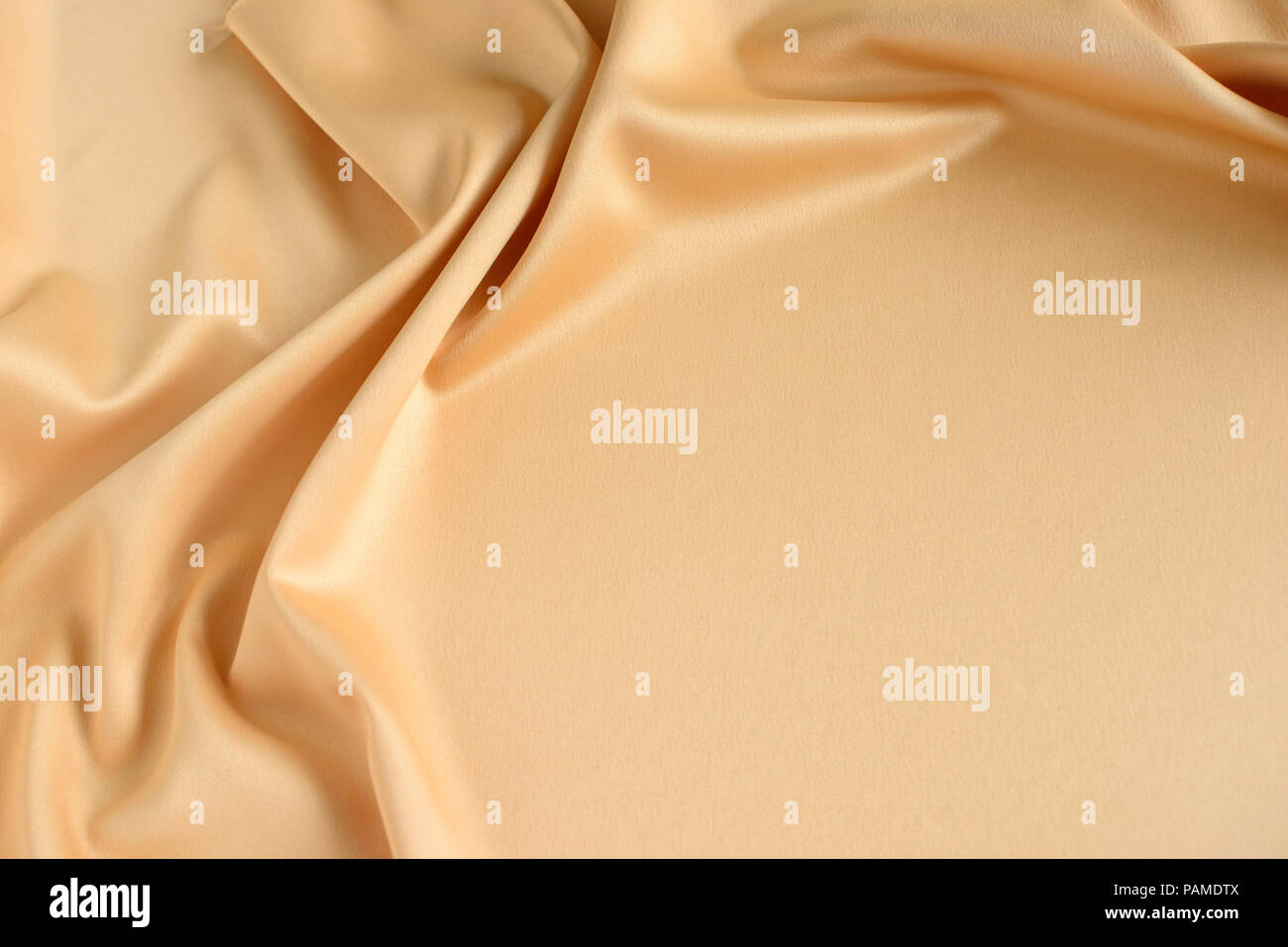 Close up di ondulazioni in color oro tessuto di seta. In raso sfondo tessili. Copia gratuita dello spazio. Foto Stock