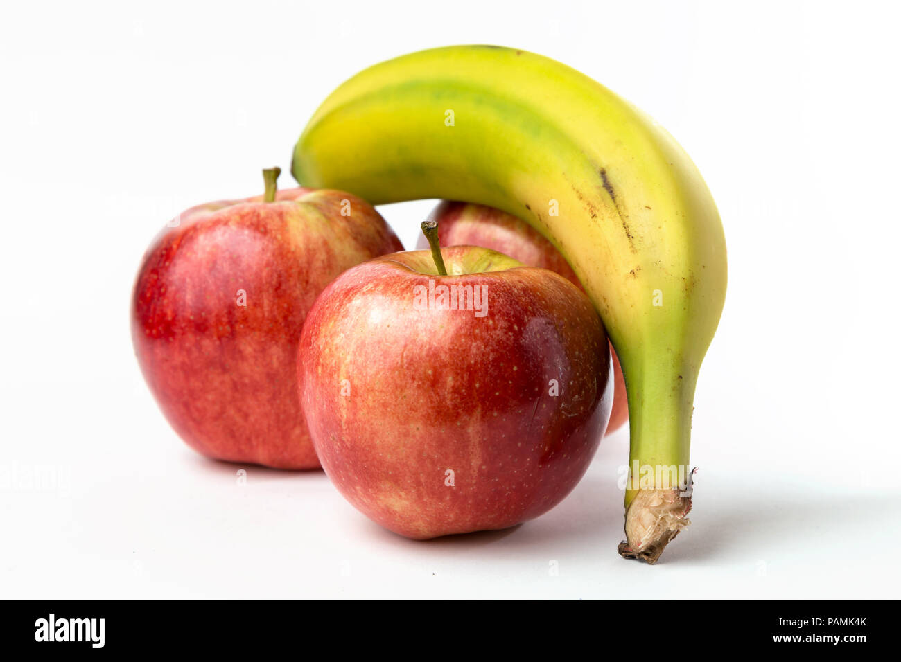 Vista di tre mele e una banana canarie su sfondo bianco Foto Stock