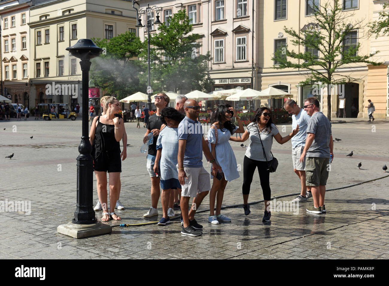 Persone il raffreddamento a spruzzo di nebulizzazione di acqua come le temperature si elevano in anni trenta a Cracovia Polonia 2018 Foto Stock