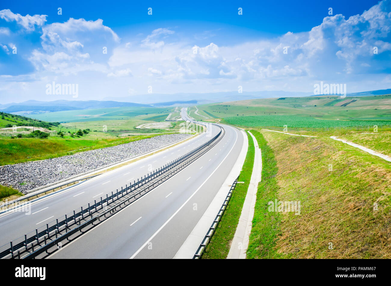 Autostrada senza traffico attraverso le colline e le montagne durante la stagione estiva in una giornata di sole Foto Stock