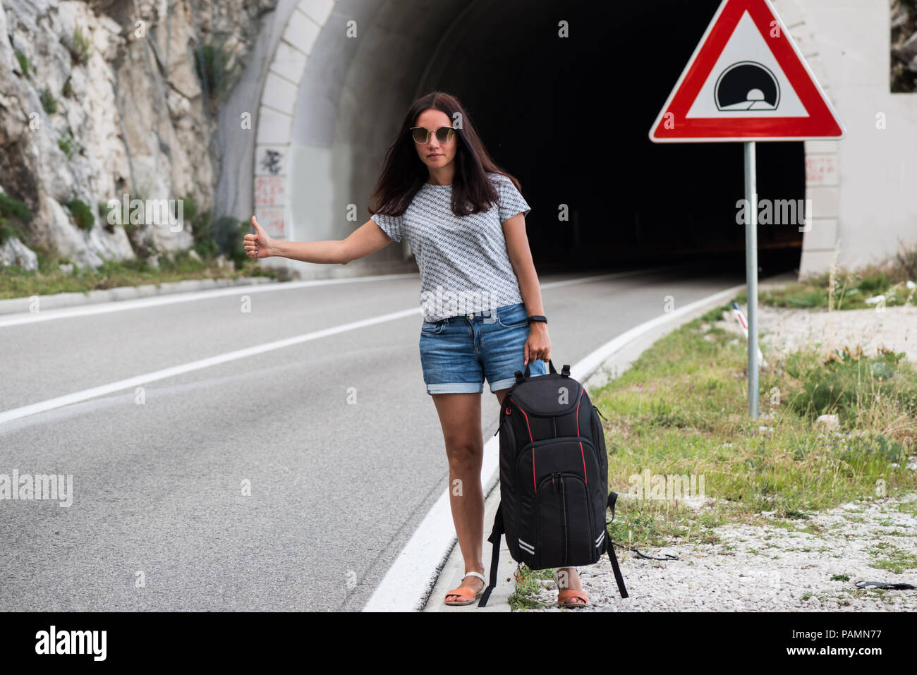 Giovani con lo zaino in spalla donna avventurosa autostop sulla strada.  Viaggiare zaini volume, imballaggio essentials. Lo stile di vita di  viaggio. Low budget di viaggio Foto stock - Alamy
