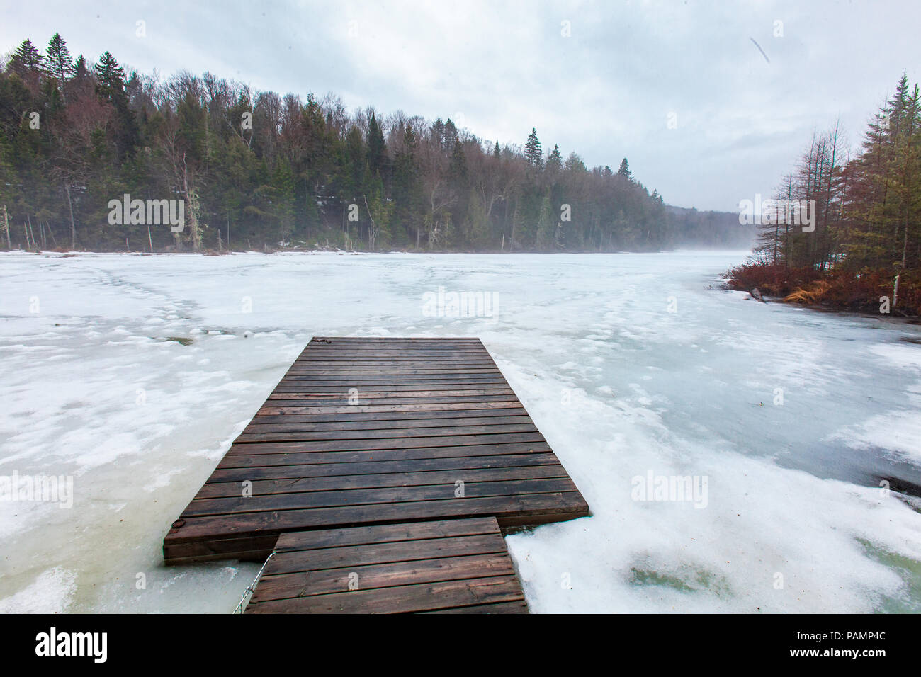 Dock su un lago ghiacciato con la nebbia, nel nord del Québec in Canada. Il lago è circondato da abeti e abeti. Foto Stock