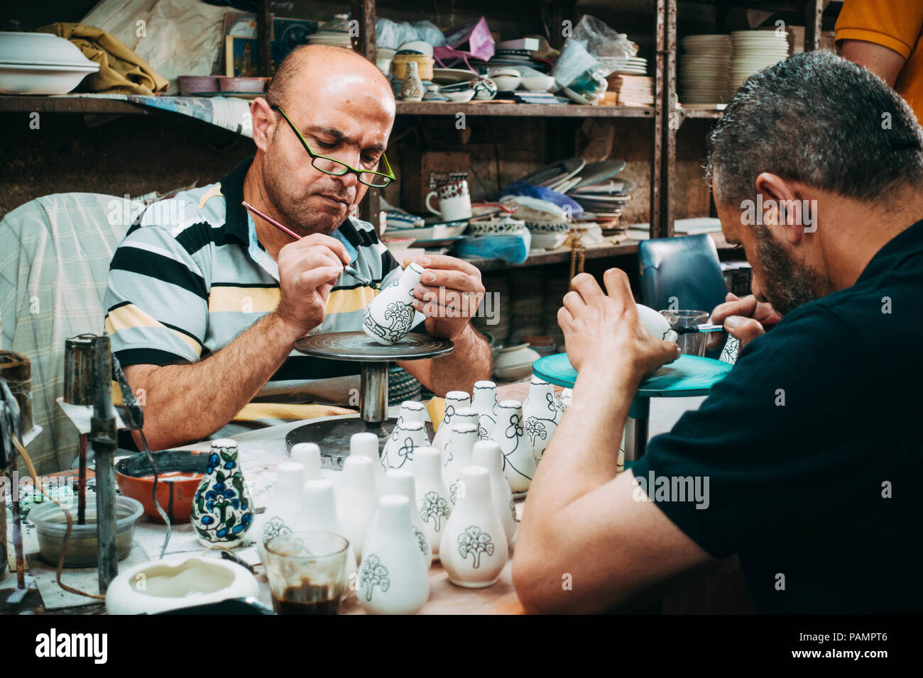 Due palestinesi vasai danno una mano di vernice decorativa per alcuni argilla bianca porcellana Foto Stock