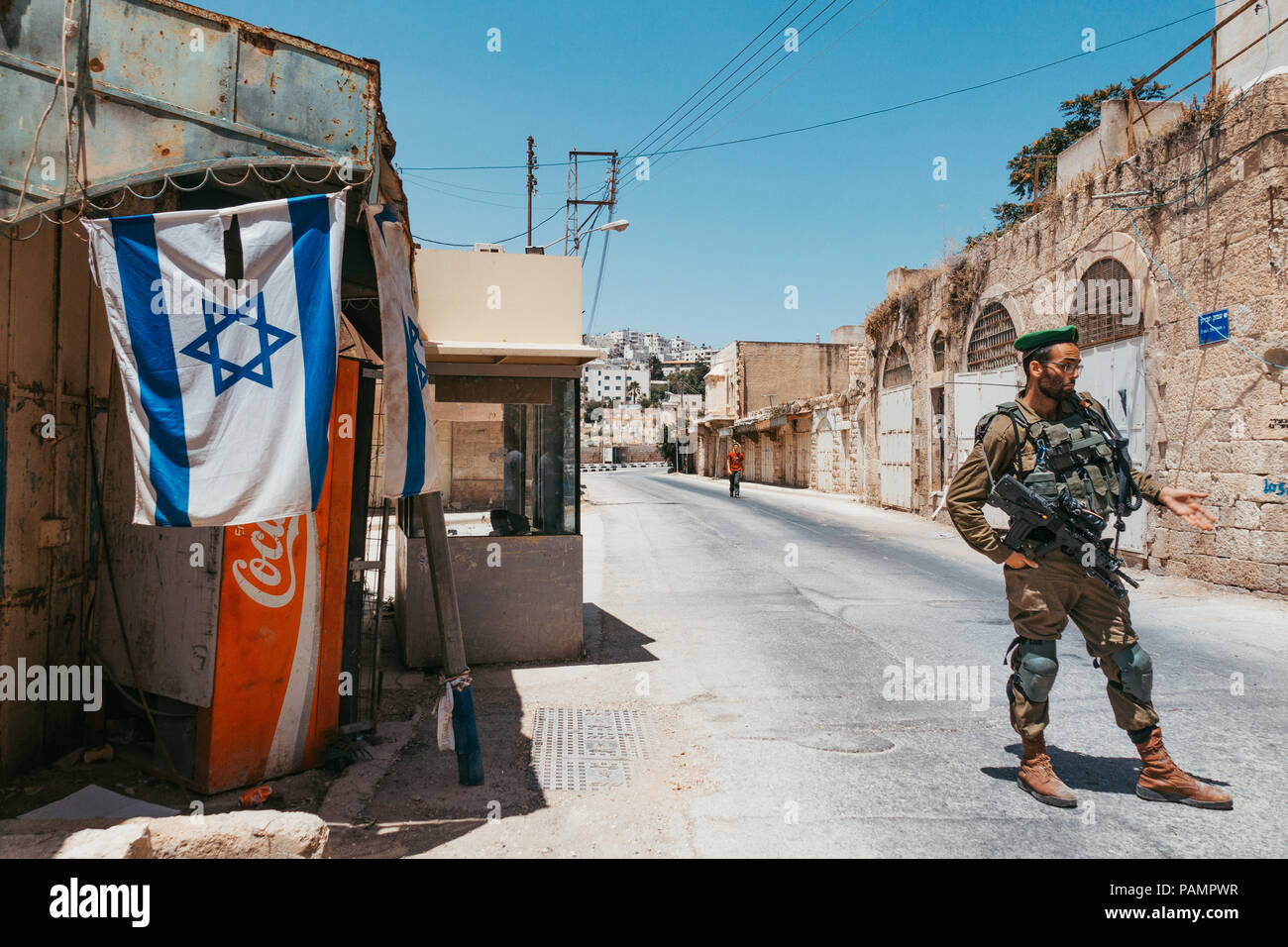 Un Forze di Difesa Israeliane soldato sta di guardia che vieta i musulmani di entrare a soli Ebrei insediamento a Hebron, West Bank occupata Foto Stock