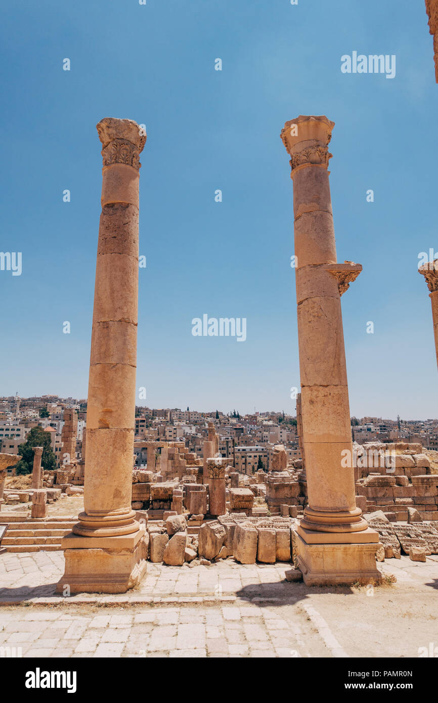 Due antiche colonne greco-romana stand tall all'entrata di un vecchio palazzo di Jerash, Giordania Foto Stock