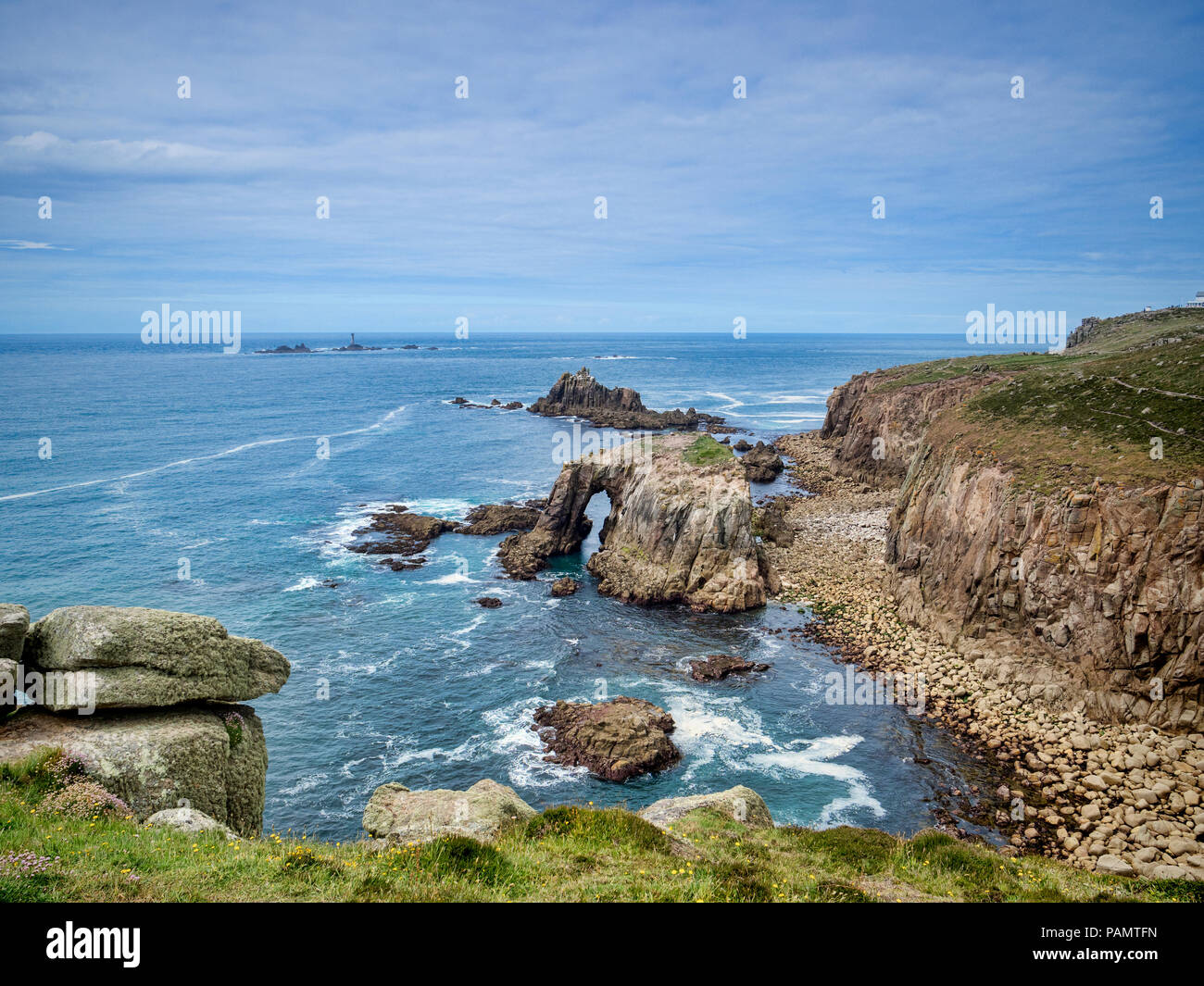 Costa rocciosa di Lands End, Cornwall, Regno Unito, con l'arco, Enys Dodnan, e la formazione di roccia del Cavaliere armato con la Longships Lighthouse offshor Foto Stock