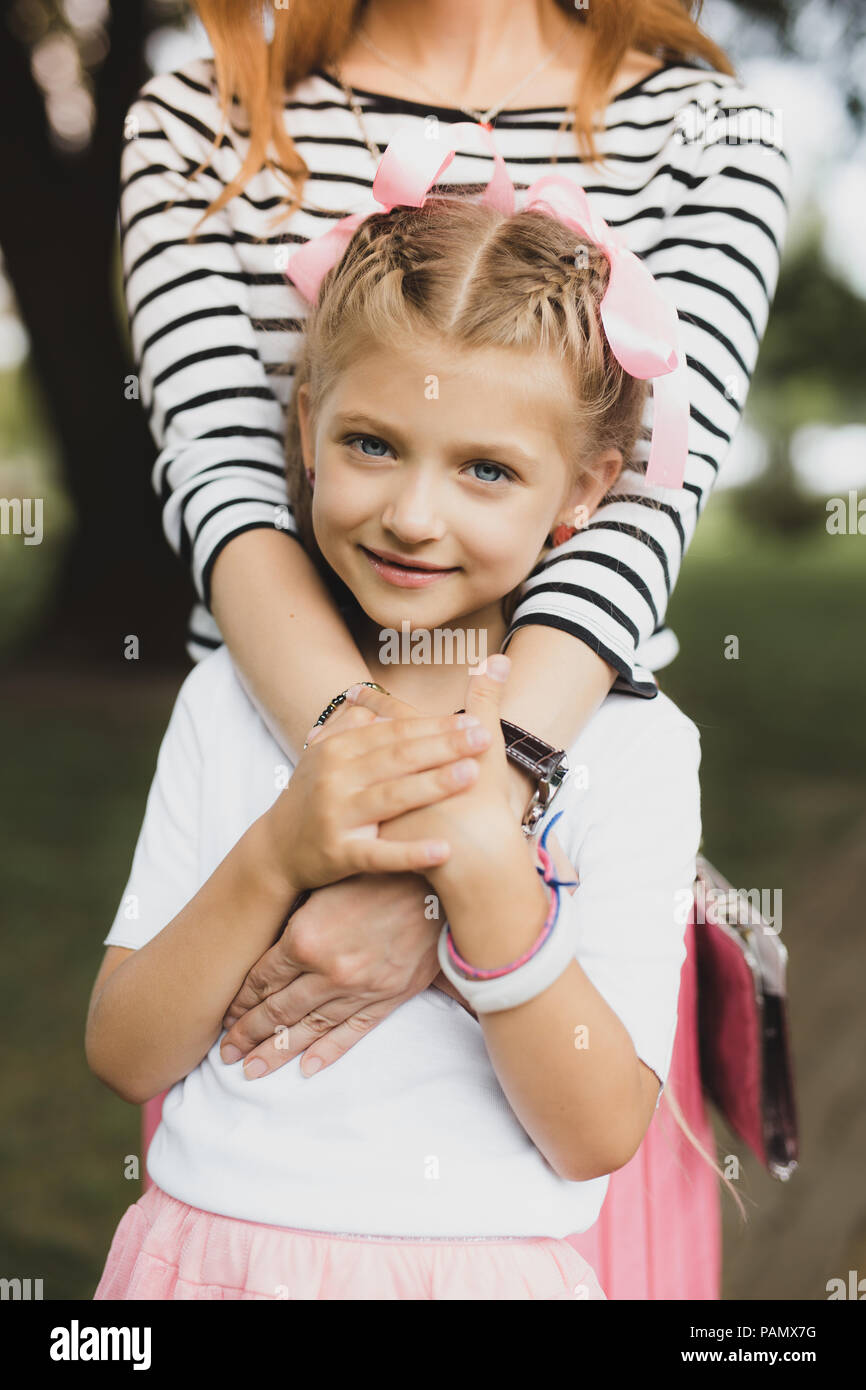 Gara figlia sorridente abbracciando la sua amorevole madre Foto Stock