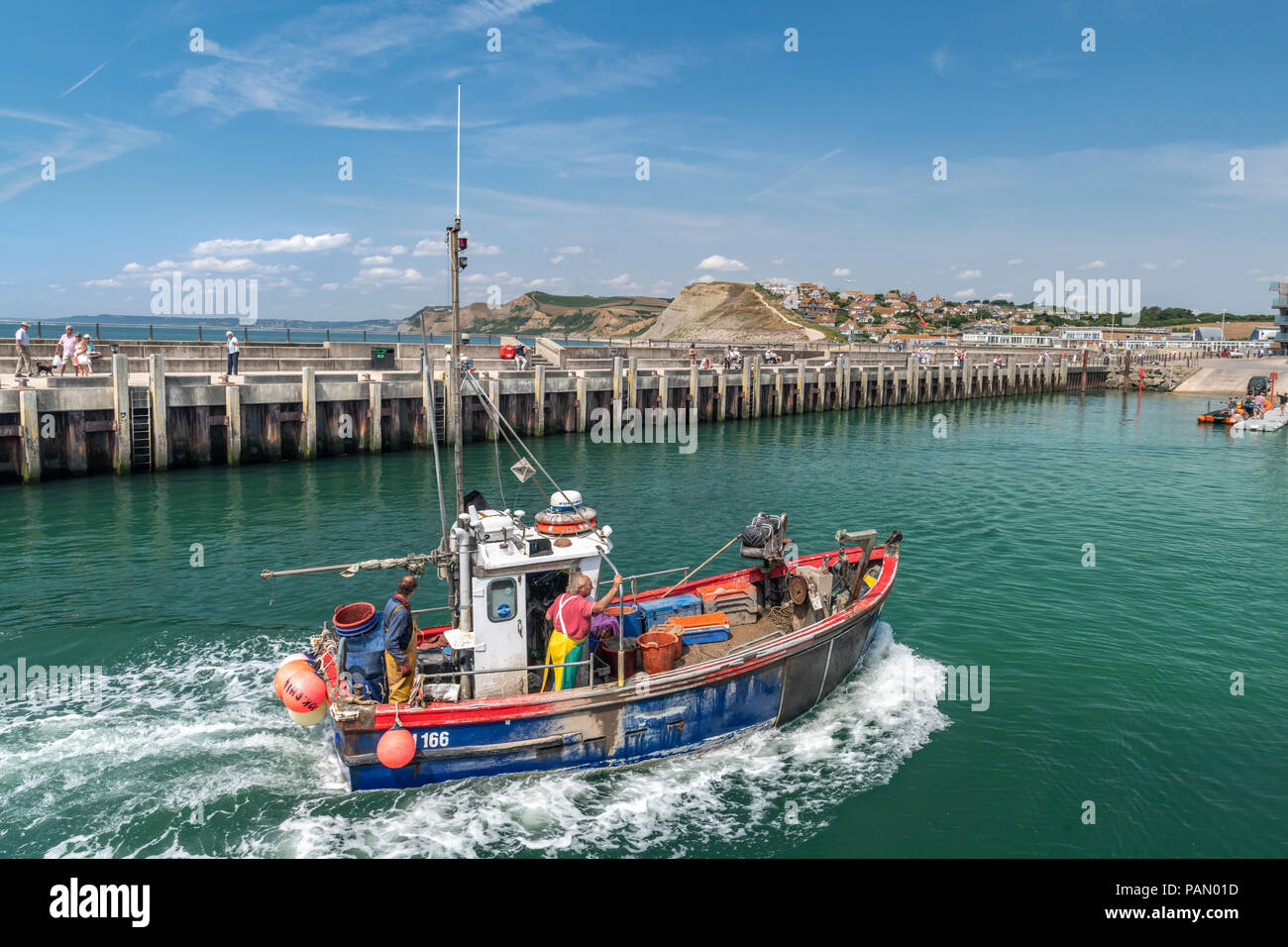 Una piccola barca da pesca restituisce con le proprie catture al pittoresco porto di West Bay nel Dorset, reso famoso come il luogo per la serie televisiva ' Foto Stock