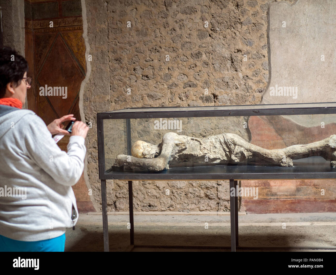 Un turista guarda impietrito corpi umani all'interno della Villa dei Misteri in Pompei in Italia. Foto Stock
