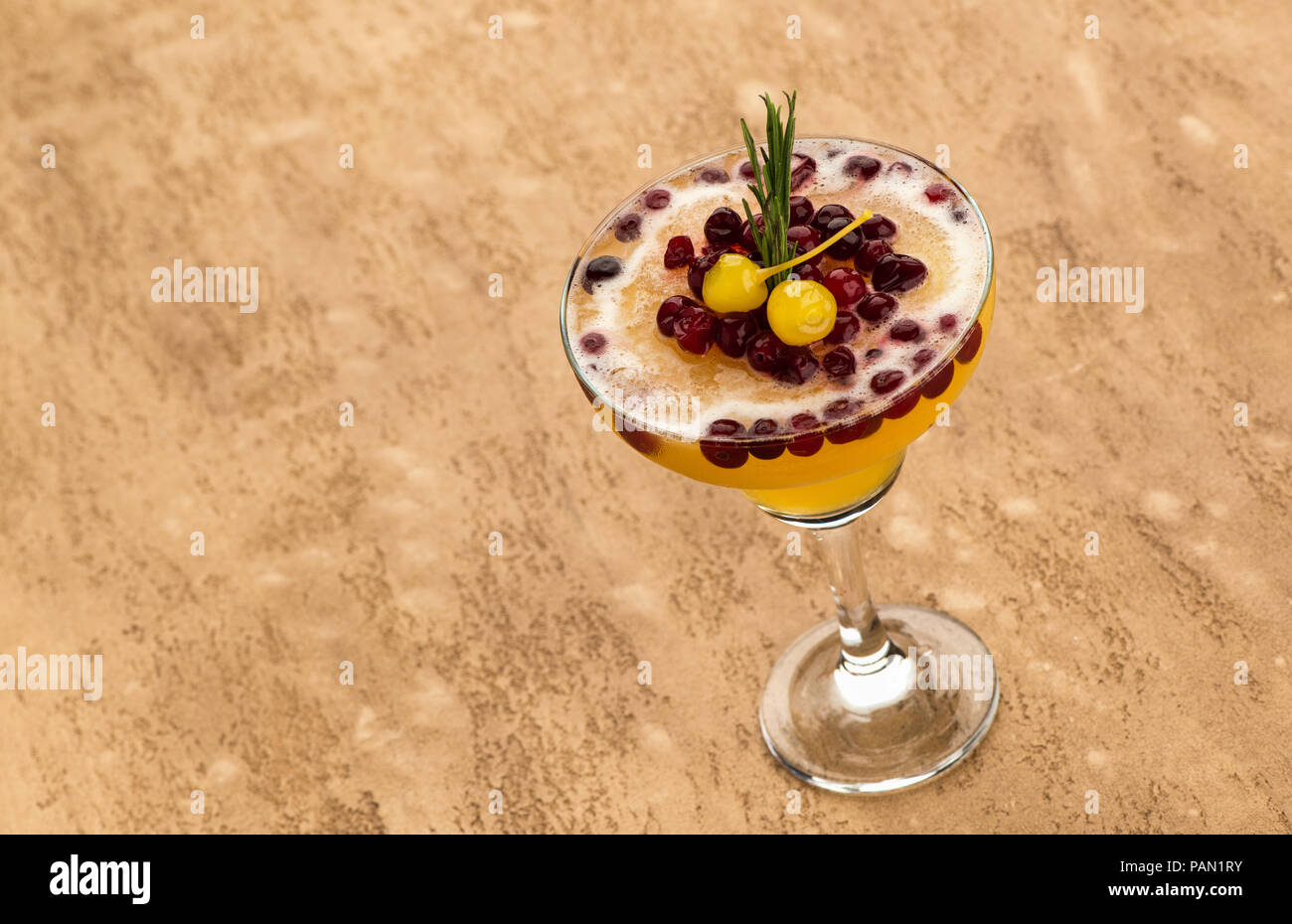 Giallo cocktail di frutta con frutti di bosco sulla luce sfondo marrone Foto Stock