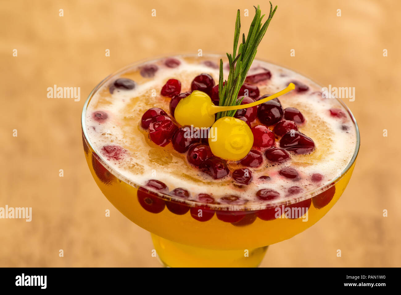 Giallo cocktail di frutta con frutti di bosco sulla luce sfondo marrone, close up Foto Stock