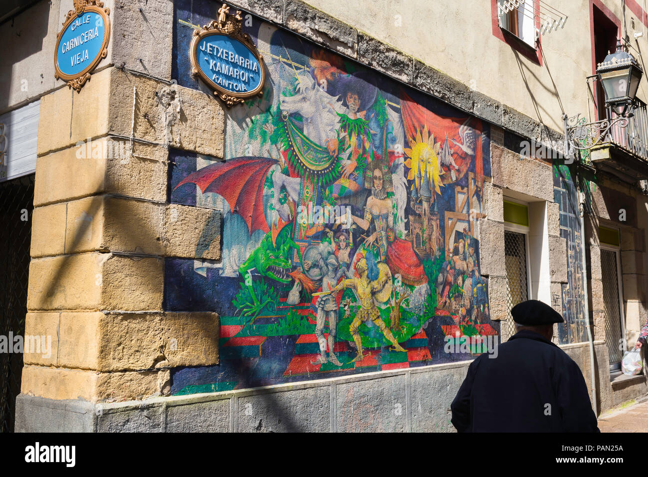 Spagna Paesi Baschi, vista posteriore di un anziano uomo che indossa un berretto oltrepassando una coloratissima parete illustrata nell'area della Città Vecchia di Bilbao, Spagna settentrionale. Foto Stock