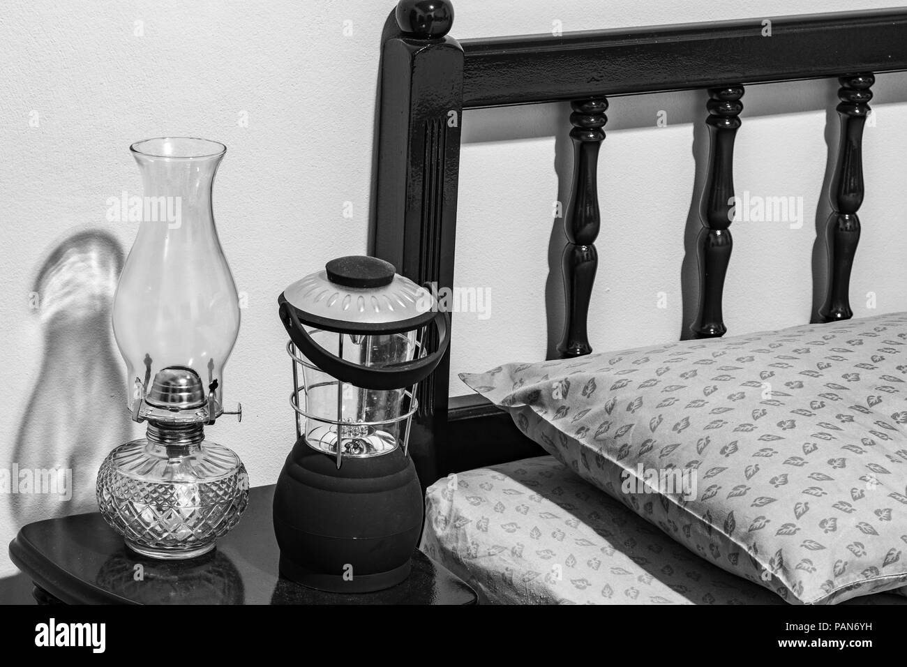 Vintage flat-stoppino kerosene olio lampada e moderno è azionato a batteria lampada sul comodino, testiera del letto, cuscino, materasso, in camera da letto. Foto Stock