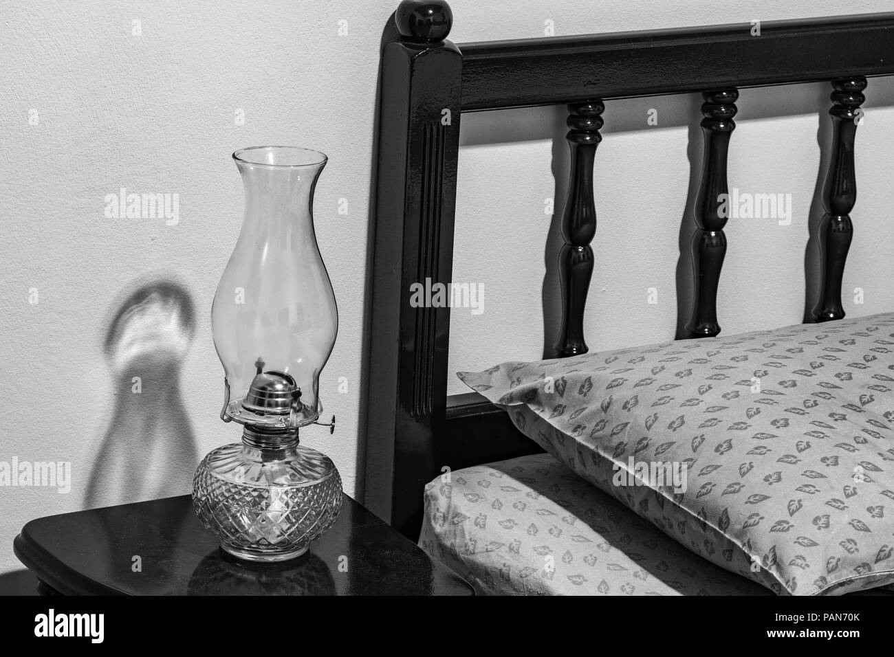 Vintage flat-stoppino Kerosene olio lampada sul comodino, testiera del letto, cuscino, materasso, in camera da letto. Foto Stock