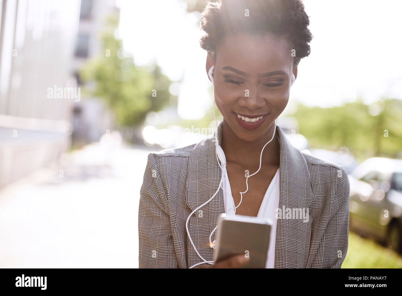 Ritratto di sorridere imprenditrice utilizza lo smartphone e gli auricolari Foto Stock