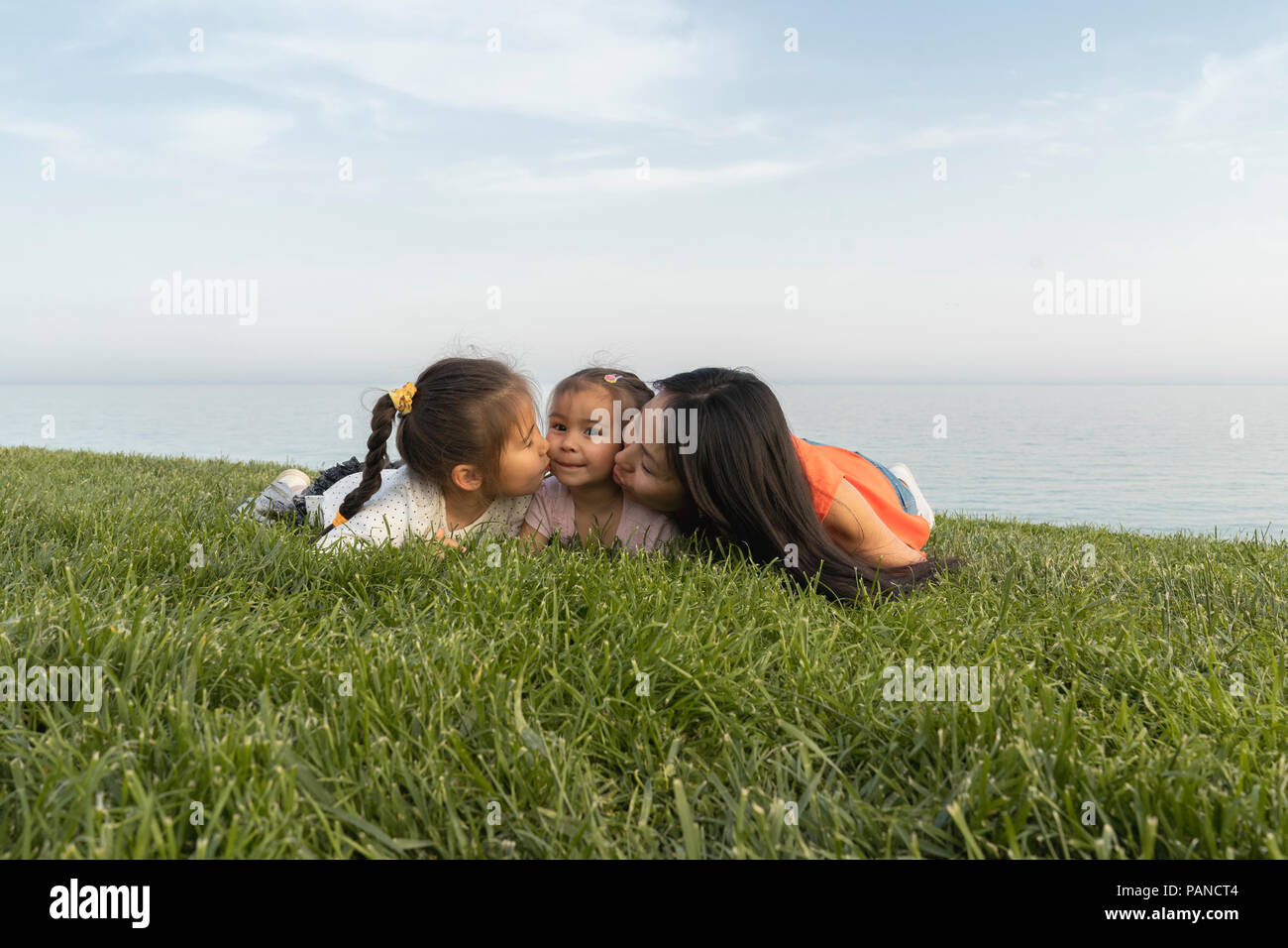Madre di due figlie kissing presso la costa Foto Stock