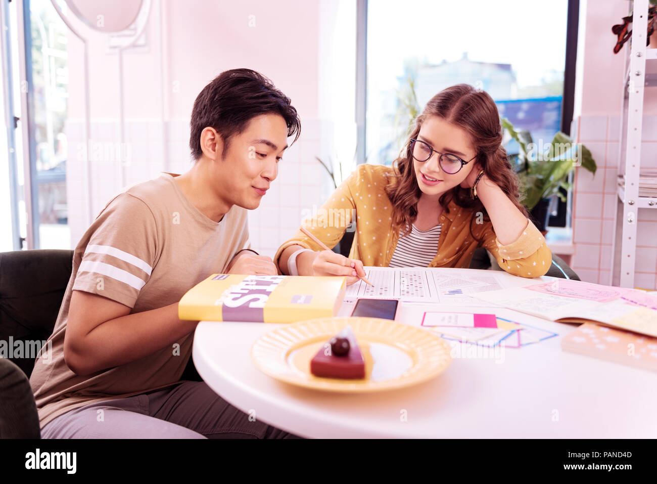 Due moderni laureandi mangiare cheesecake e studiare Foto Stock