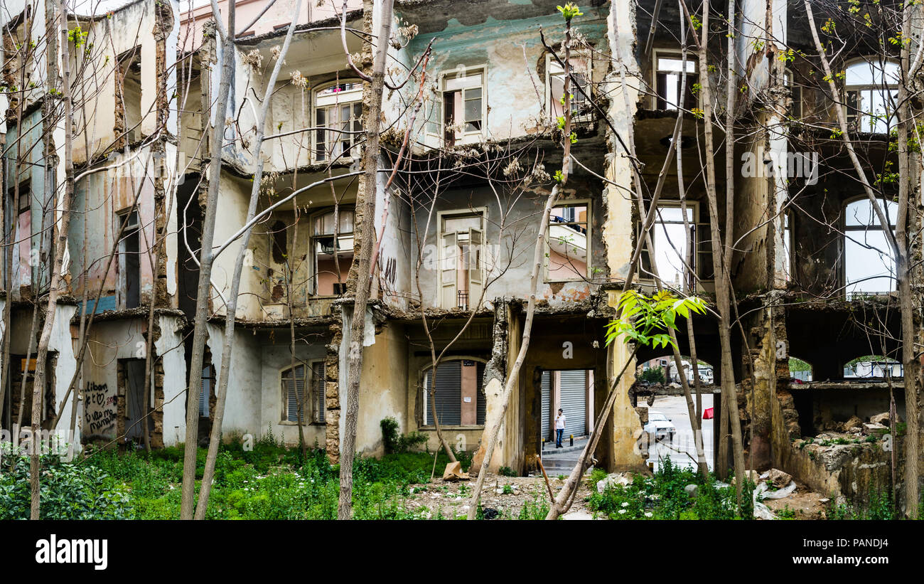 Le rovine e ricoperta di vegetazione la facciata interna di un vecchio edificio storico, danneggiate e distrutte durante la guerra civile a Beirut, Libano Foto Stock