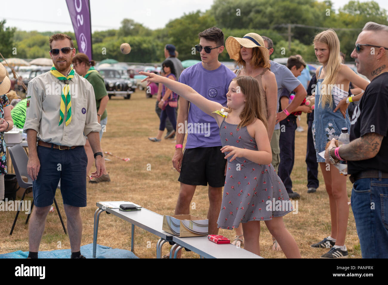 Ragazza di gettare una palla di legno in corrispondenza di una piastra di scout smashing stallo a una fiera di paese in Hampshire Foto Stock