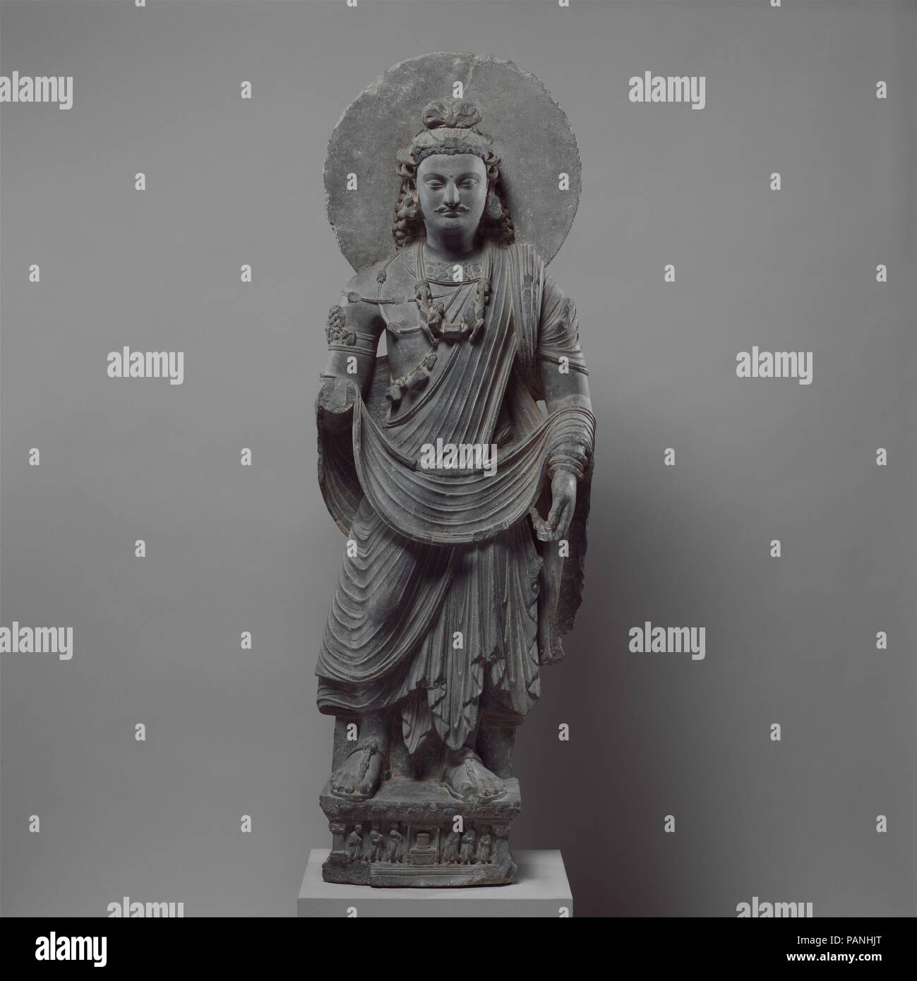 Bodhisattva permanente (Maitreya Buddha del futuro). Cultura: Pakistan (antica regione del Gandhara). Dimensioni: H. 64 1/4 in. (163,2 cm); W. 21 a. (53,3 cm); D. 8. (20,3 cm). Data: ca. 3. secolo. Questo bodhisattva possono essere identificati come Maitreya dal labbro dell'acqua sacra pallone nella sua mano sinistra e mediante il suo loop topknot, un'acconciatura comune alle immagini di Maitreya. Sulla base, donatore figure venerate un reliquiario buddista che poggia su un trono bassa sotto una tettoia. Museo: Metropolitan Museum of Art di New York, Stati Uniti d'America. Foto Stock