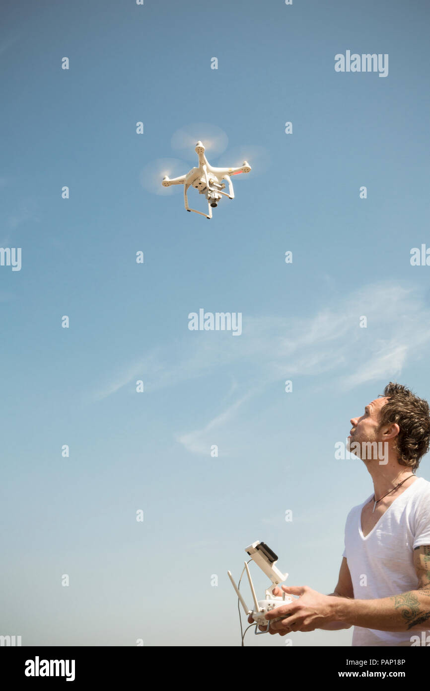 L'uomo flying drone sotto il cielo blu Foto Stock