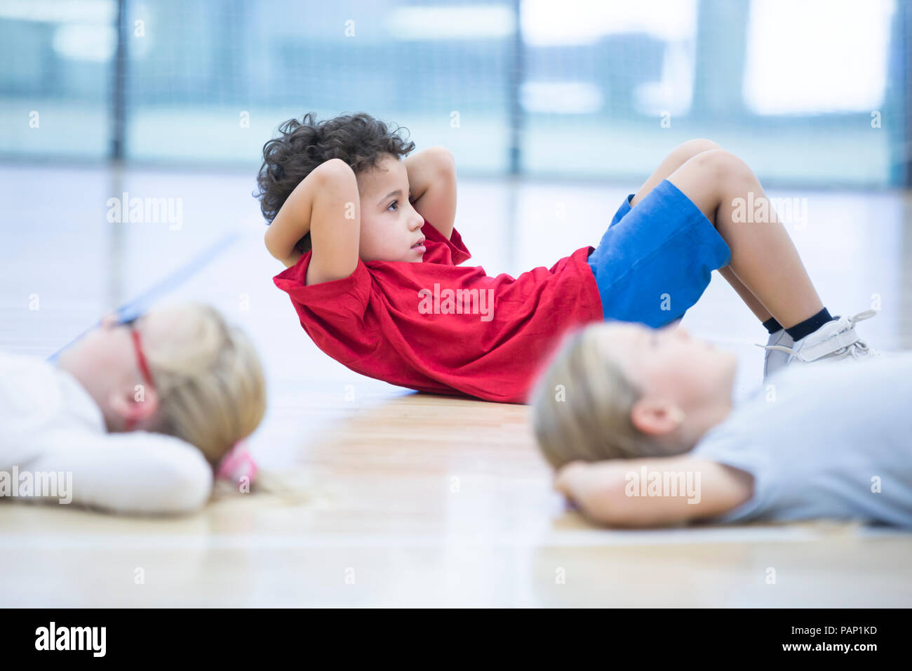 Gli alunni di esercitare nella palestra di classe Foto Stock