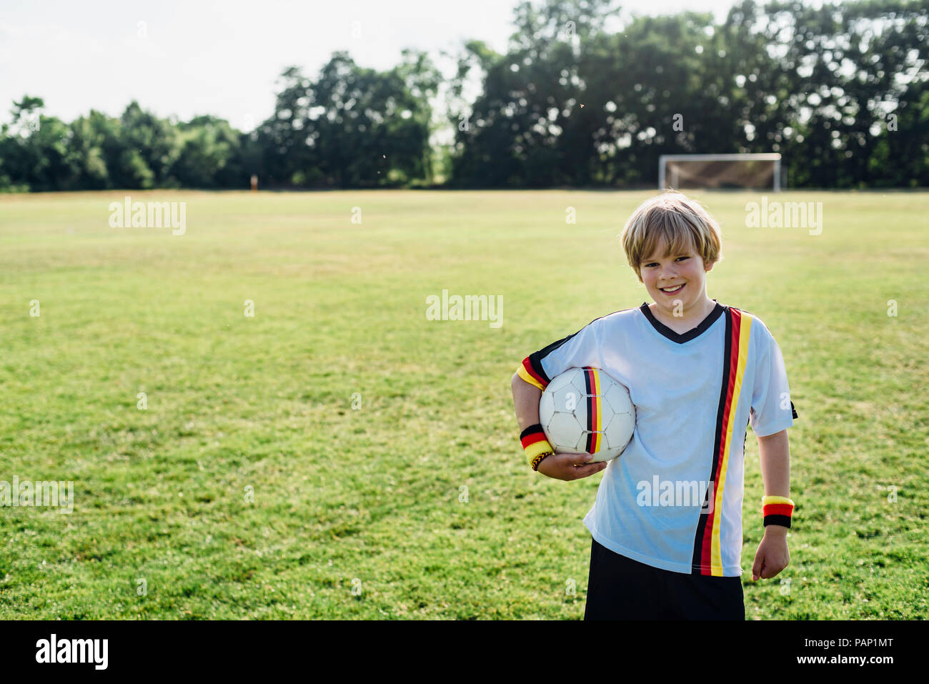 Ragazzo che indossa calcio tedesco shirt, tenendo il calcio Foto Stock